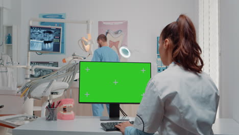 mujer usando teclado y computadora con pantalla verde