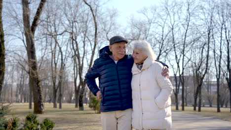 senior couple holding hands, walking and hugging in the park on a winter day