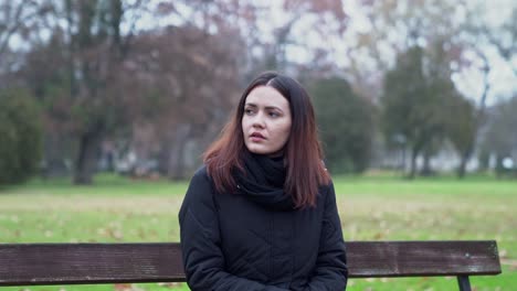 Young-woman-sitting-on-a-bench-looking-around-and-waiting-for-someone