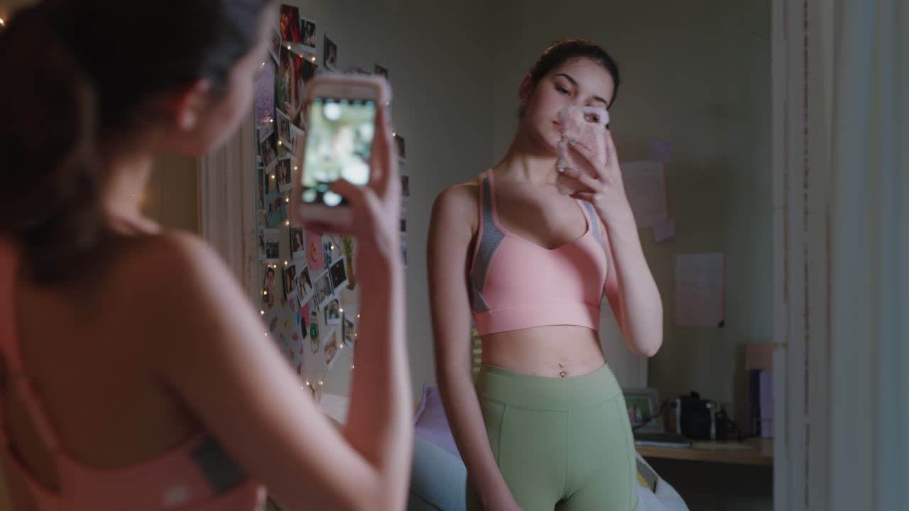 ragazza adolescente felice che si fa una selfie usando lo smartphone che posa allo specchio che condivide la moda elegante sui social media che si gode il fine settimana a casa immagine di sé adolescente