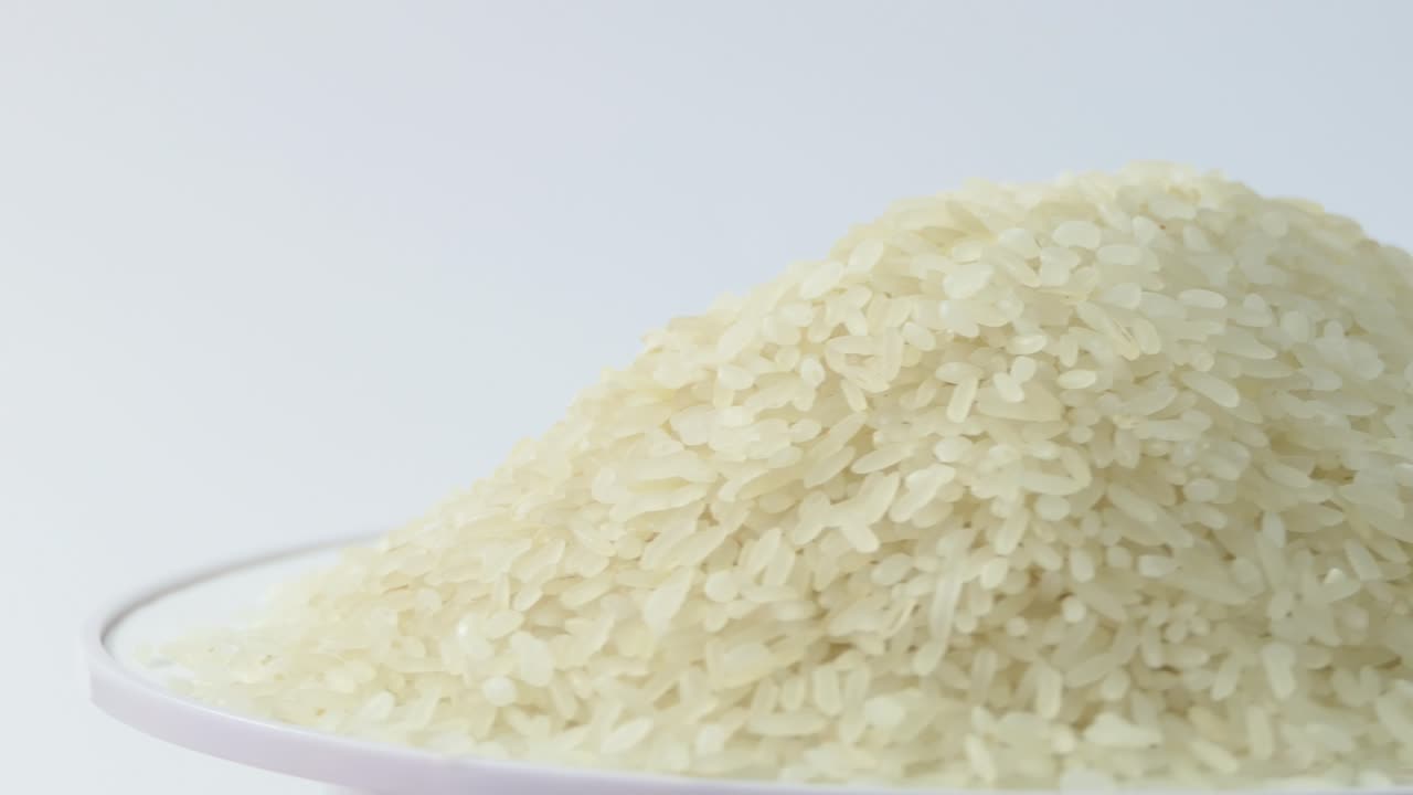 Macro white raw rice texture, food background, vegetarian healthy eating product. Rotating close up of a pile of raw rice