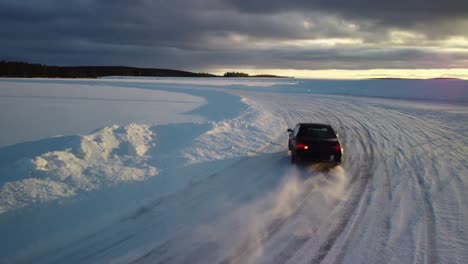 dark cheap sport cars drifting on frozen lake in finland during golden hour – aerial winter landscape with a frozen race track low altitude