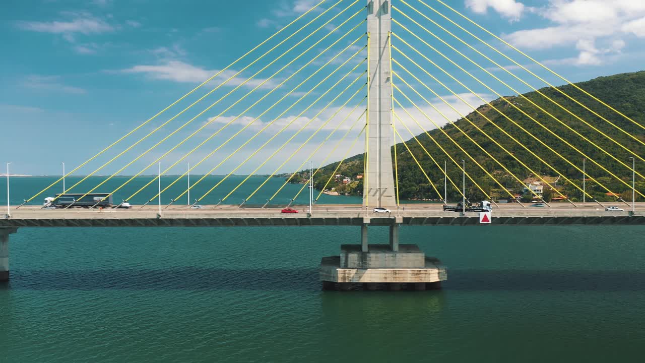 청록색 바다 위의 콘크리트 사장교 트래픽의 드론 공중 측면 패닝 뷰