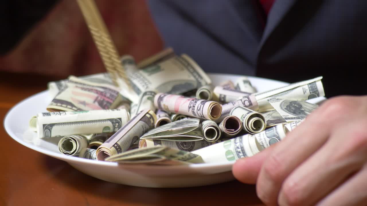 Mani di un uomo d'affari con le bacchette e rotoli di dollari. Mangia dollari. 4K.
