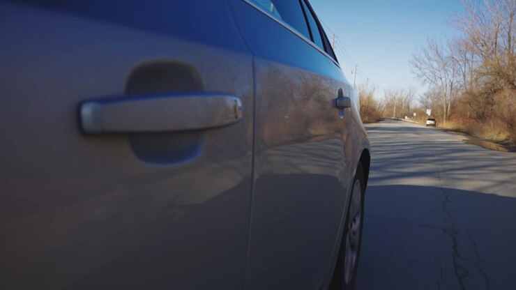 Maniglie della portiera sinistra di un'auto che viaggia su una strada asfaltata in una giornata di sole - Primo piano