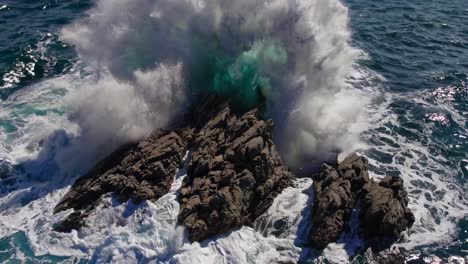 aerial video captures waves crashing on rocky shore, showcasing dynamic ocean movement from a high