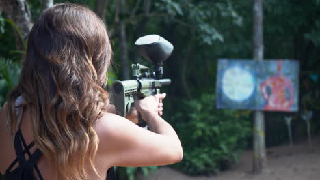 una mujer activa con una pistola de paintball practica disparar a un objetivo - concepto: frustración, ira, venganza, relación, ruptura, ex novio