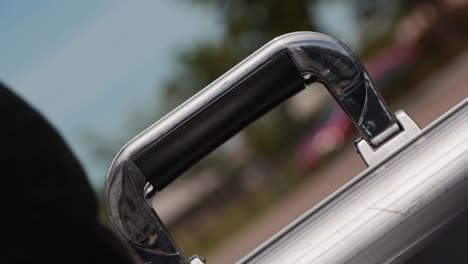 a man grabs hold of the handle of a stainless steel briefcase and picks it up