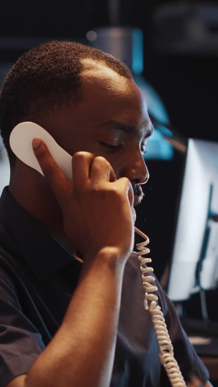 Video verticale: uomo afroamericano che risponde a una telefonata da telefono fisso a tarda notte