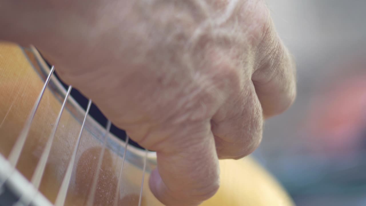 손가락 을 사용 하고 기타 를 연주 하는 노인 의 손 의 극단적 인 근접