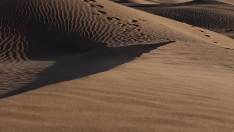 Sand-Weht-über-Sanddünen-Mit-Entfernten-Fußabdrücken-In-Der-Wüstenlandschaft-Des-Nahen-Ostens-In-Der-Nähe-Von-Dubai-In-Den-Vereinigten-Arabischen-Emiraten