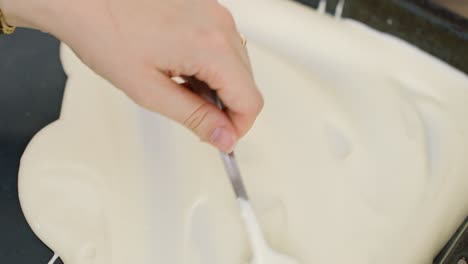 smoothly spreading rich tiramisu cream in a glass baking pan, preparing for layering