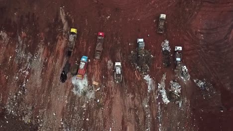 straight down aerial view of dump trucks unloading garbage at a landfill