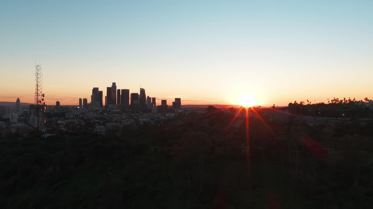 Wide aerial dolly shot of the downtown skyline during sunset in Los Angeles, California. 4K
