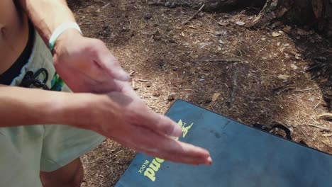 young climber clapping his hands rubbing magnesium into it to prepare for climb