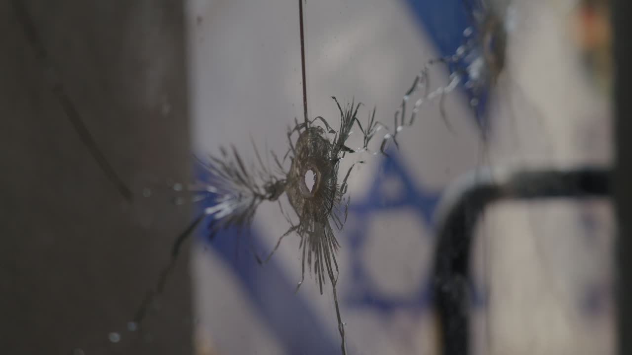 Rack focus from Israeli Flag to Broken glass window gunshot, Kibbutz Nir Oz after Hamas attack - slow motion