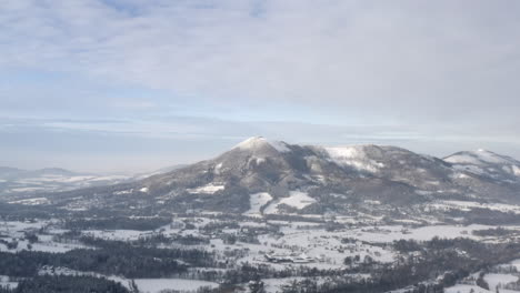 Snow-capped-mountain-range-above-a-forest-winter-landscape,-Czechia