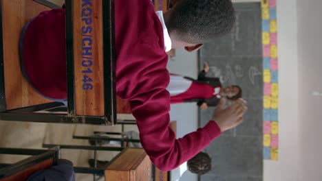 teacher with student raising hand in class in african school - vertical shot