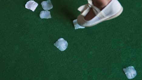 slow motion shot of little girl wearing cute white shoes with ribbon walking on flowers petals