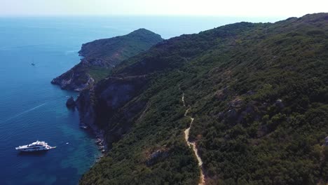 Toma-Aérea-De-Una-Impresionante-Prueba-De-Senderismo-A-Lo-Largo-De-La-Costa,-La-Gente-Camina,-Los-Barcos-Flotan