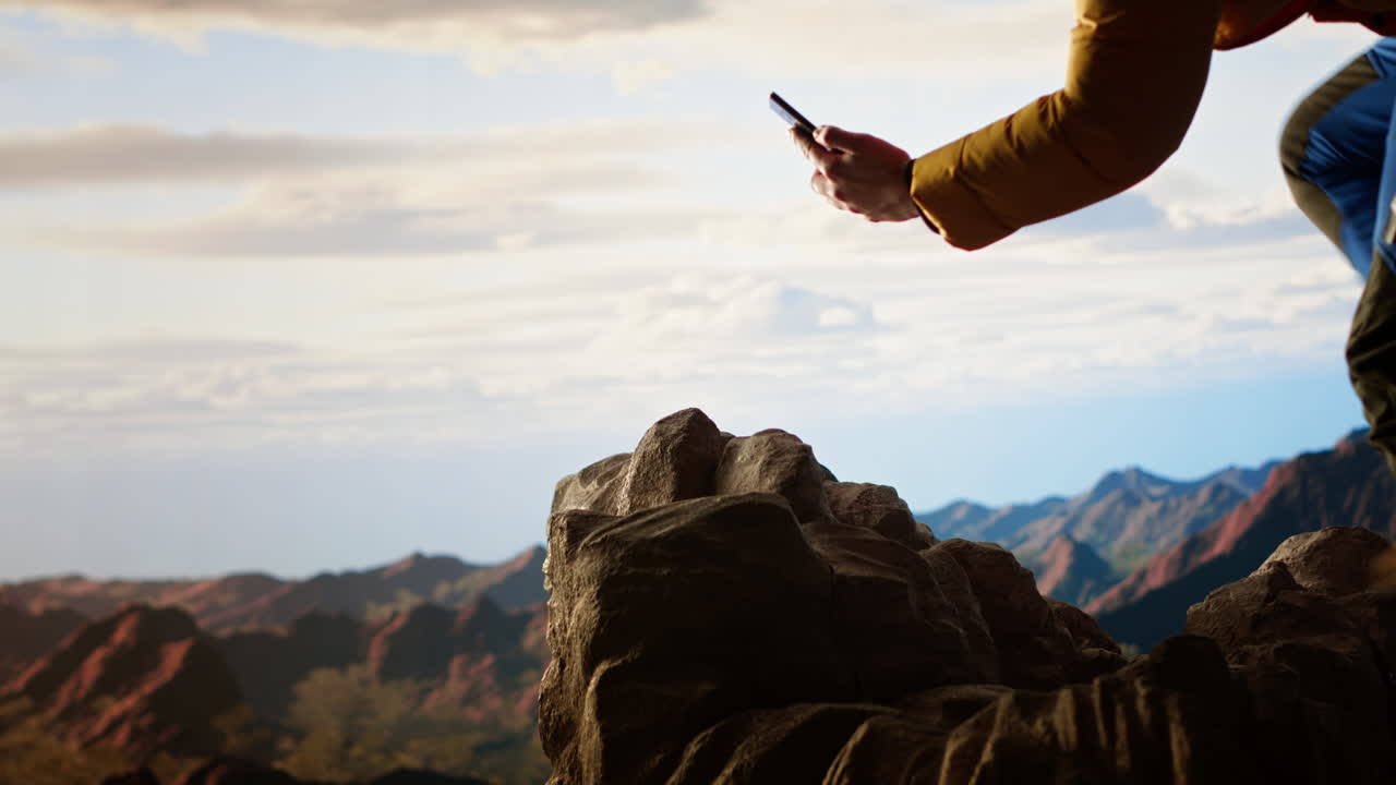 Un alpinista negligente distratto dal suo smartphone sta cadendo sulla cima di una montagna
