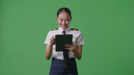 asian woman pilot using a tablet while standing in the green screen background studio