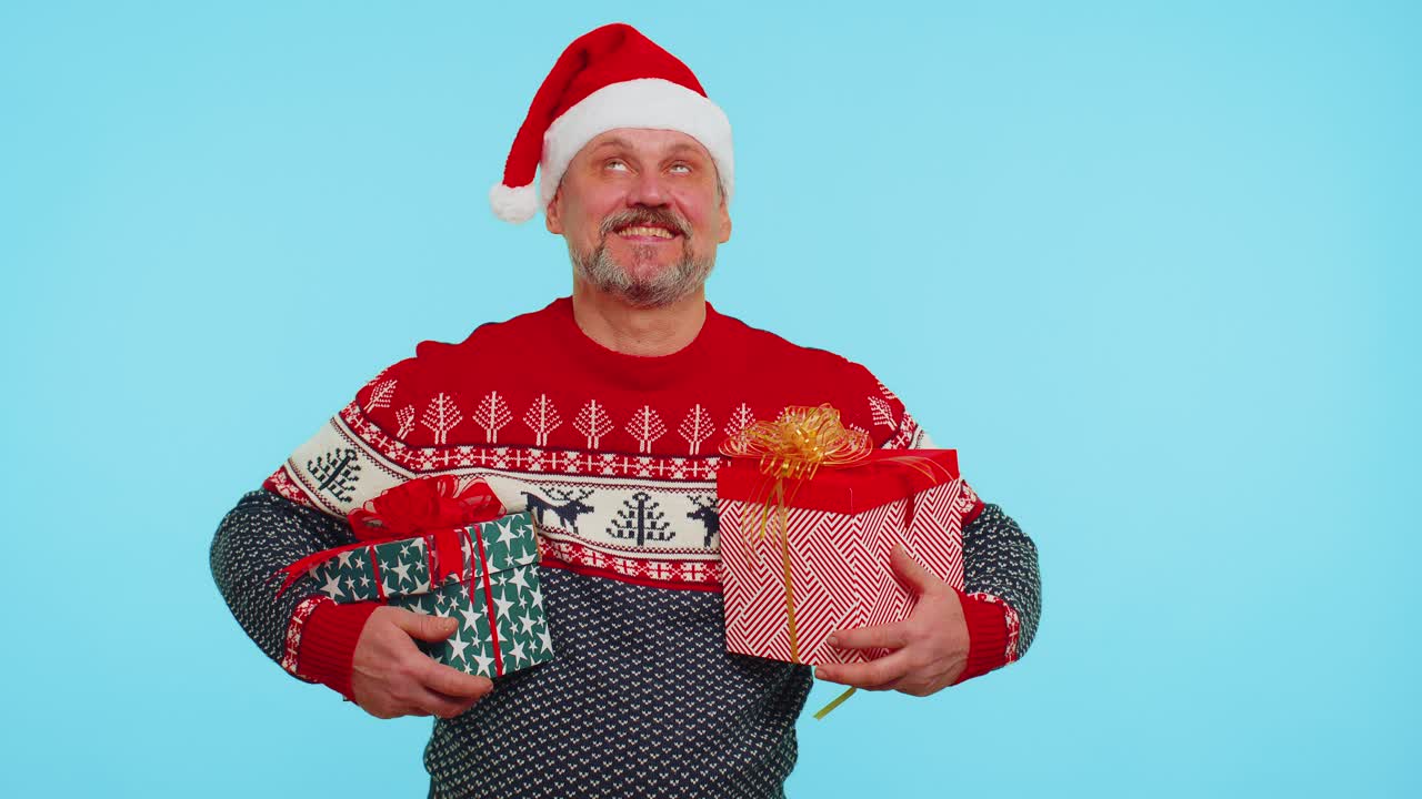 Cheerful man in santa sweater presenting two christmas gift boxes stretches out his hands to camera