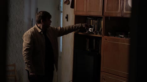 a man collects old things in a box to move from his old house. he leaves his old apartment and is sad