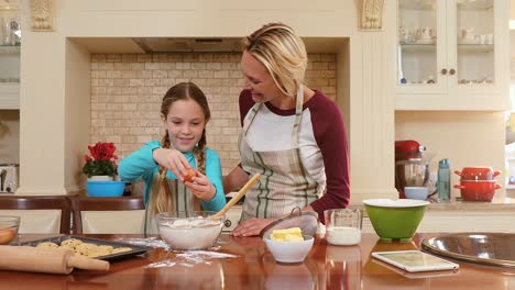 Smiling-daughter-breaking-an-egg-and-mother-assisting-her-4K-4k