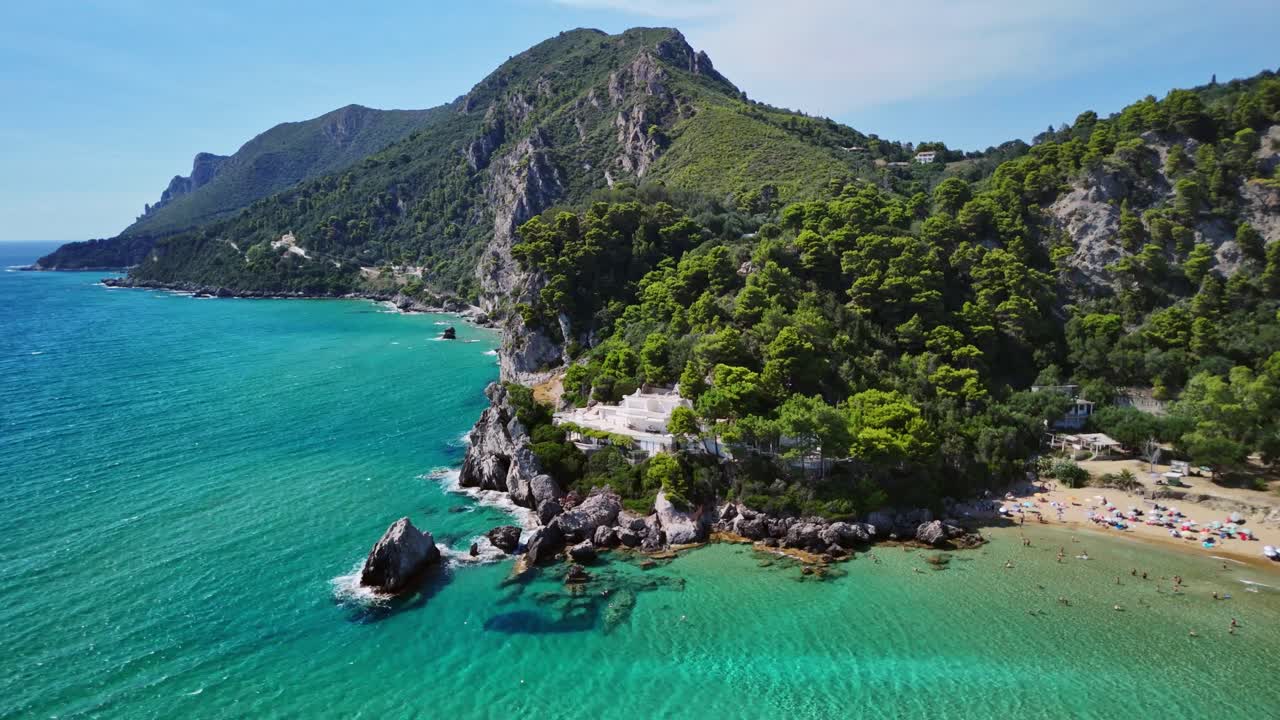 Aerial view of a scenic coastline with lush trees by clear turquoise waters