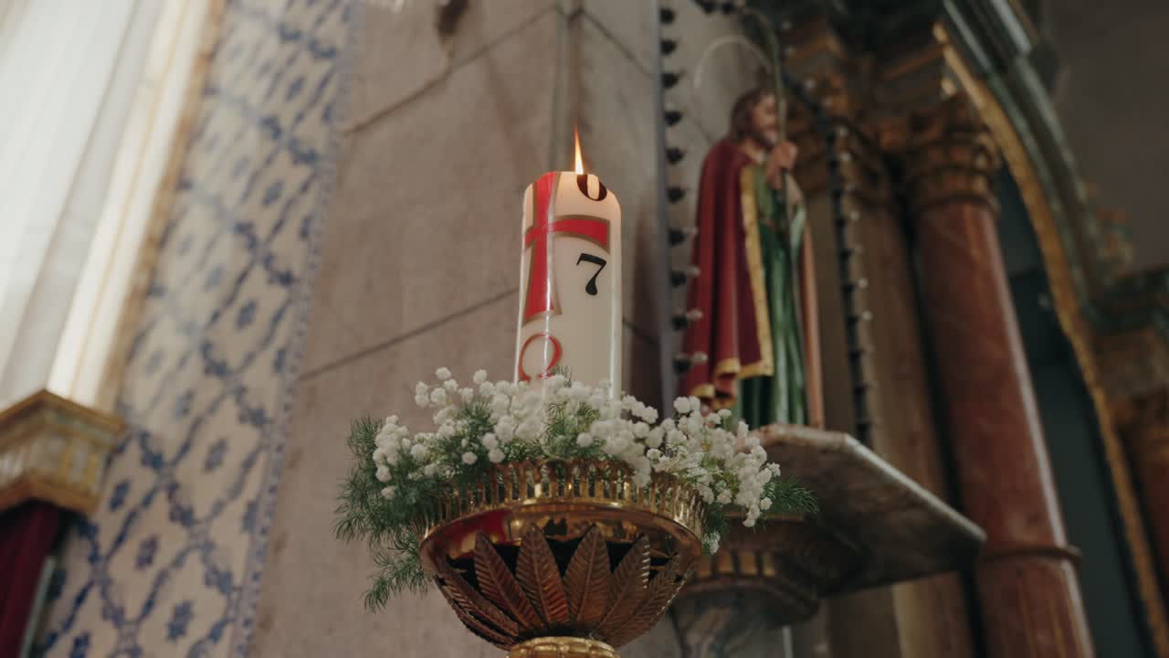 Warm lit baptismal candle adorned with delicate floral base