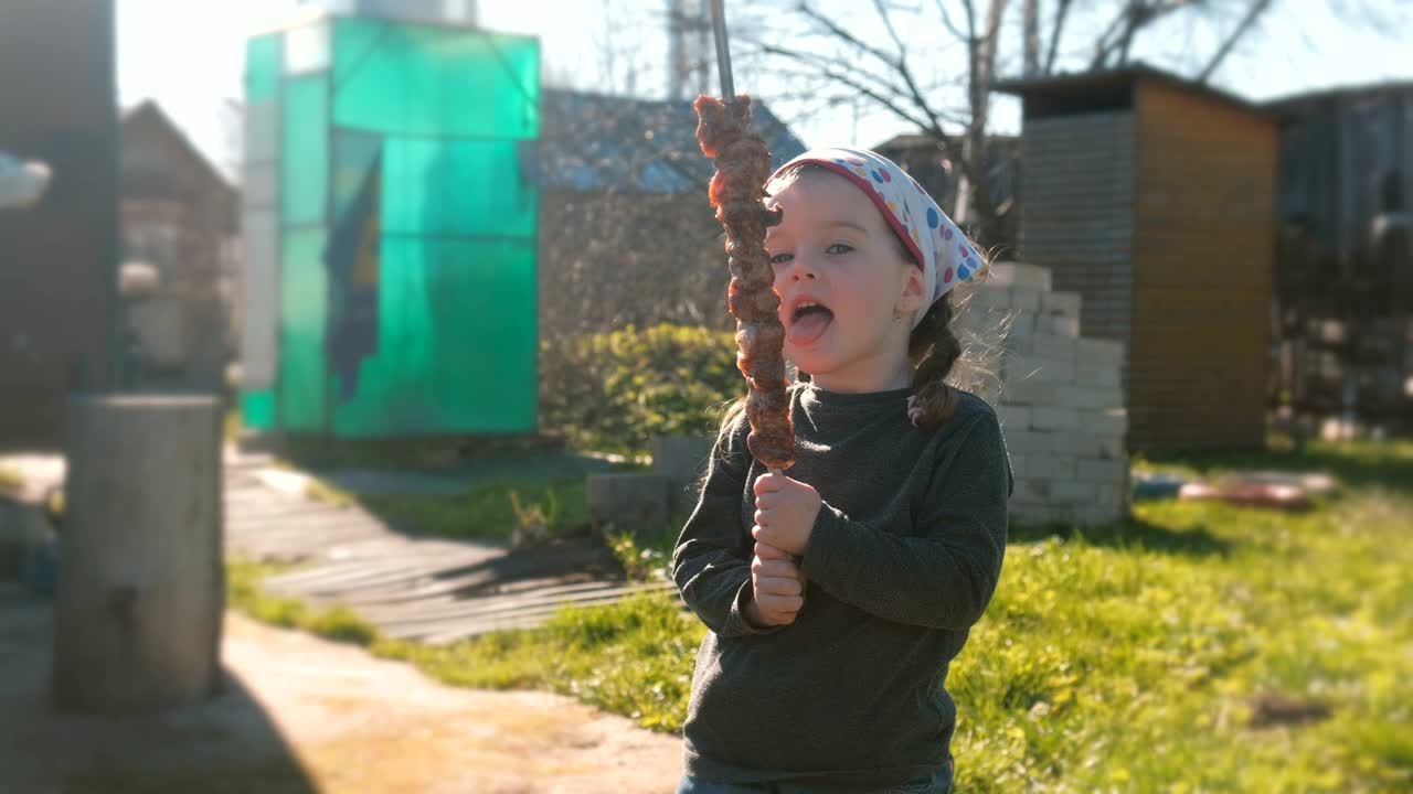 Little cute girl wants to eat barbecue shashlik on a skewer.