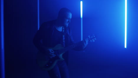 guitarist performing under blue lights