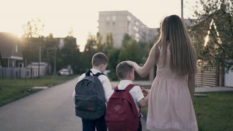 seguimiento de cámara lenta madre joven va con los niños de la escuela le dicen acerca de los éxitos