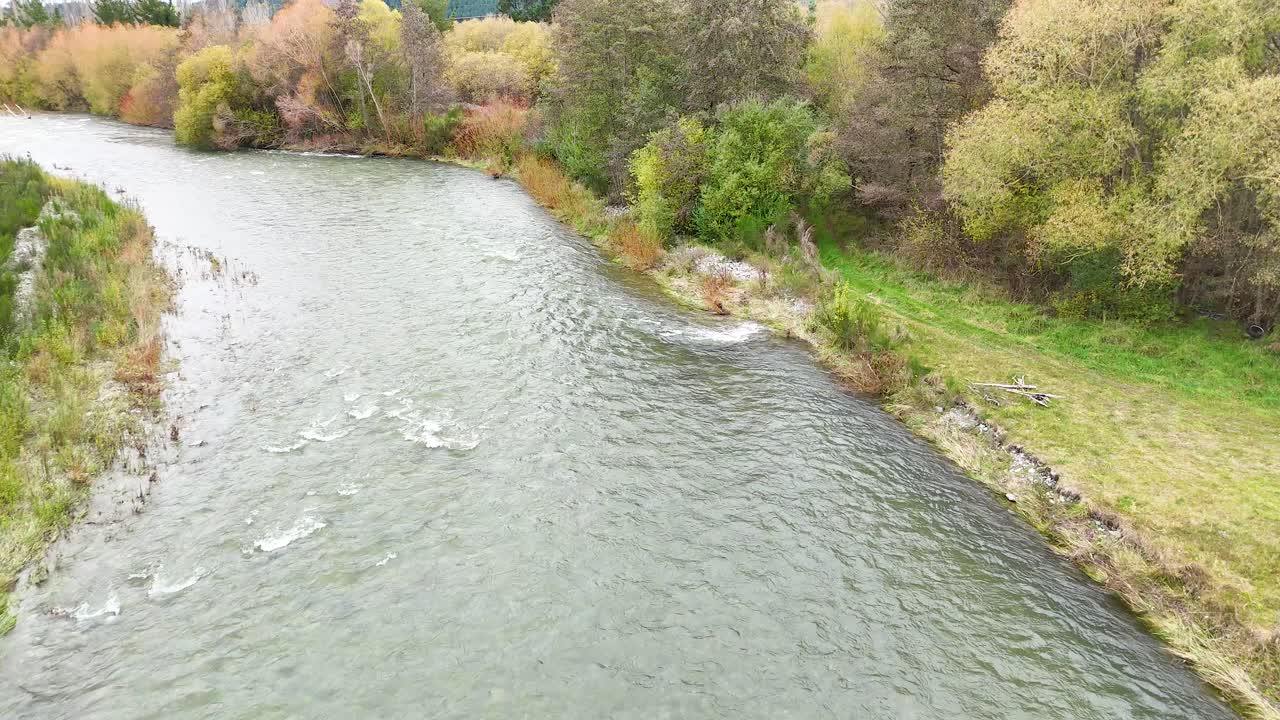 Aerial view of a tranquil river winding through lush greenery, captured in soft daylight at Lake Tekapo, New Zealand