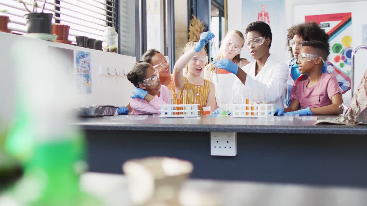 maestra diversa y escolares felices teniendo clase de ciencias en el laboratorio escolar