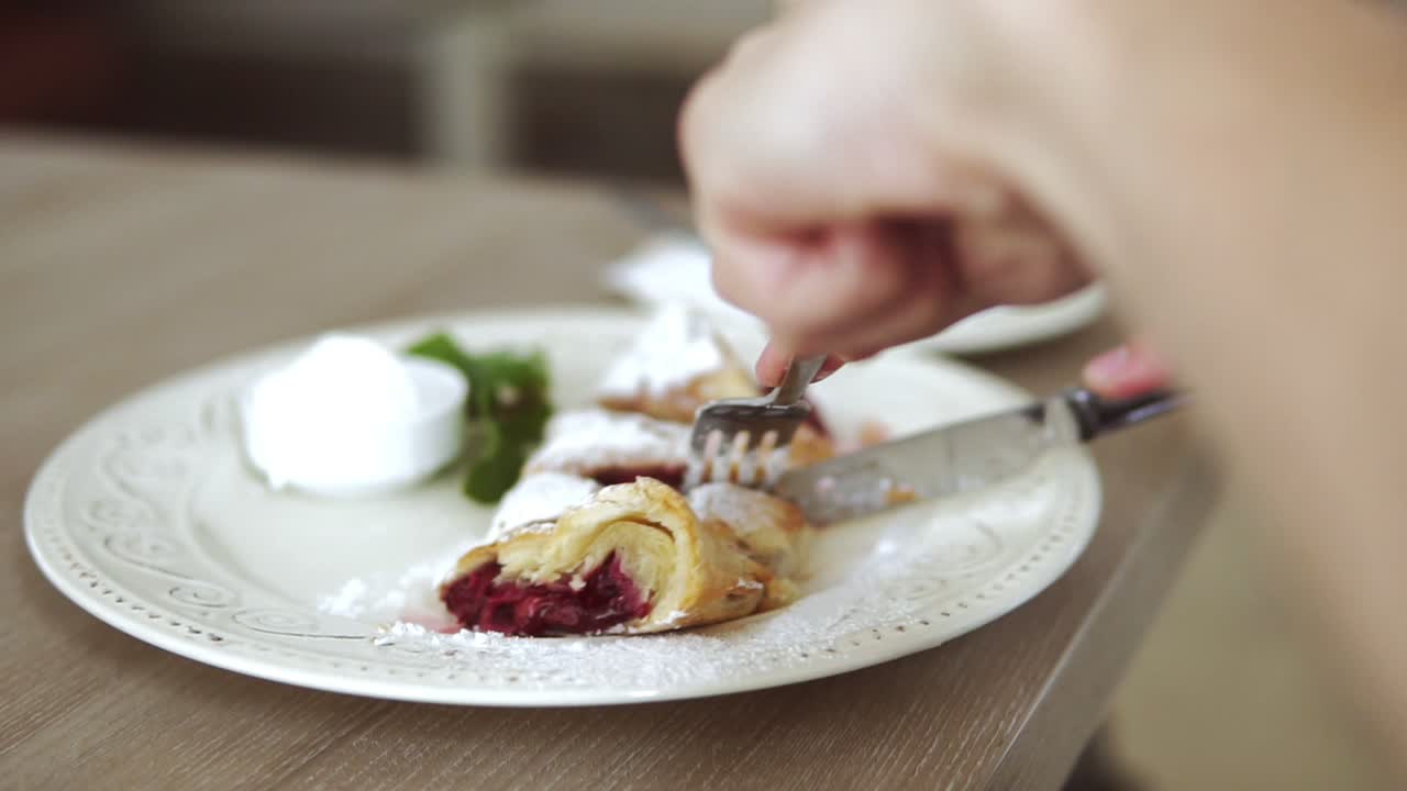 Unrecognizable man in white t-shirt taking desert strudel at the restaurant using fork and knife. Slow Motion shot