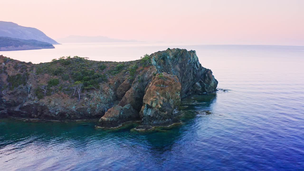 Ripida scarpata rocciosa che si protende nel mare calmo all'alba, Mesudiye, Datça.