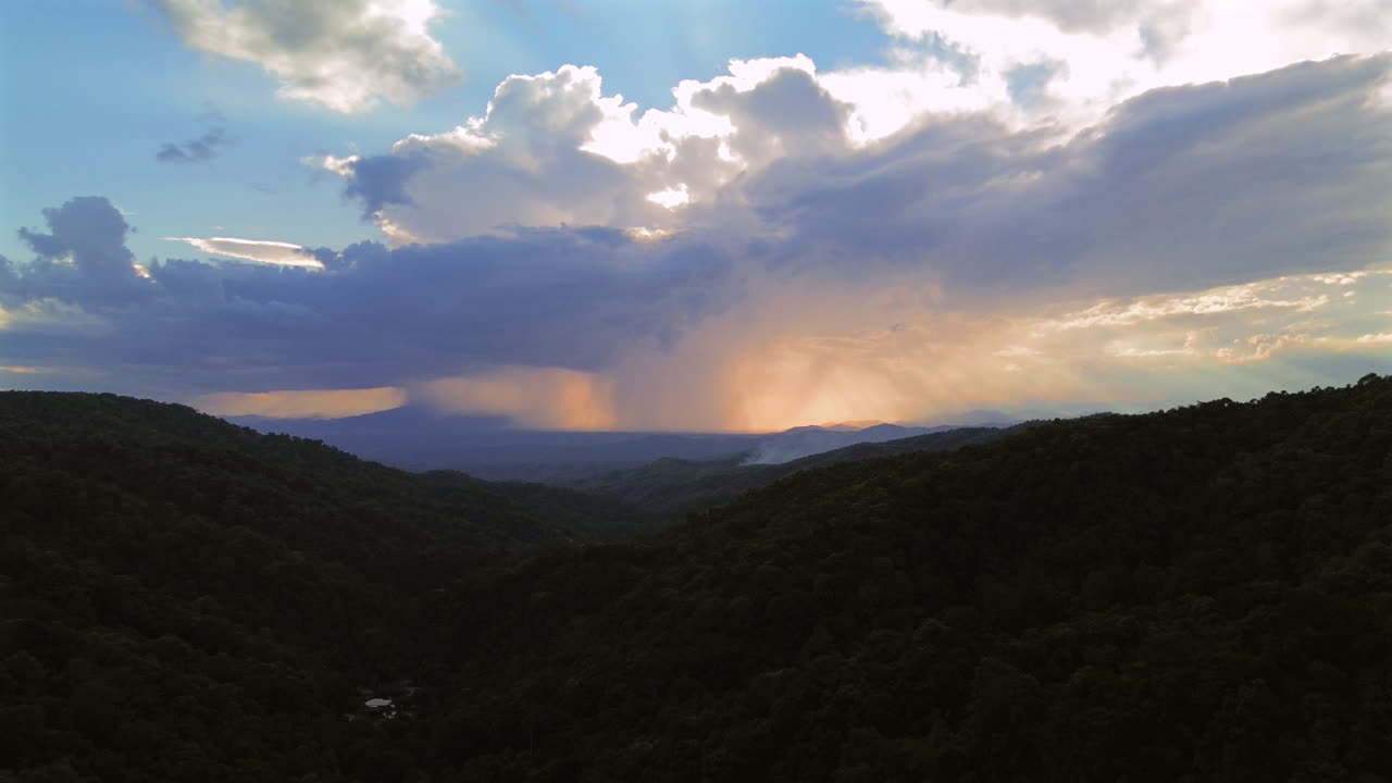 Dark clouds gather over green hills as a stormfront moves across the landscape