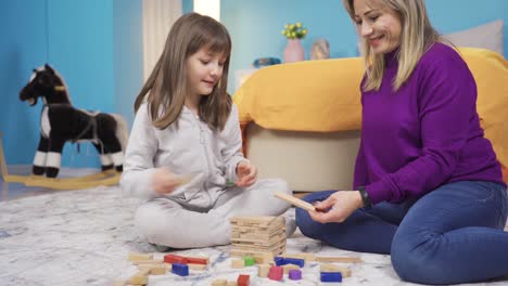 mamá y una niña linda jugando juntos, rompecabezas. niña y madre felices.