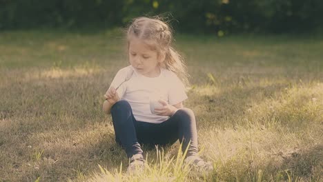 little girl looks at metal spoon holding yogurt container