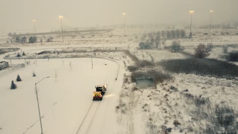 mini bulldozer drives through empty parking lot, snow-covered, storm