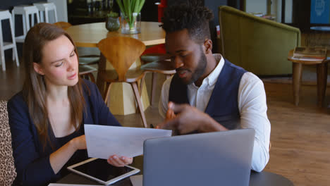 Front-view-of-young-cool-mixed-race-business-team-planning-and-sitting-at-table-of-modern-office-4k