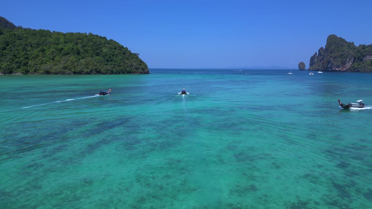 la bahía de koh phi phi, coloridos barcos tradicionales de cola larga están flotando en aguas tranquilas de color turquesa