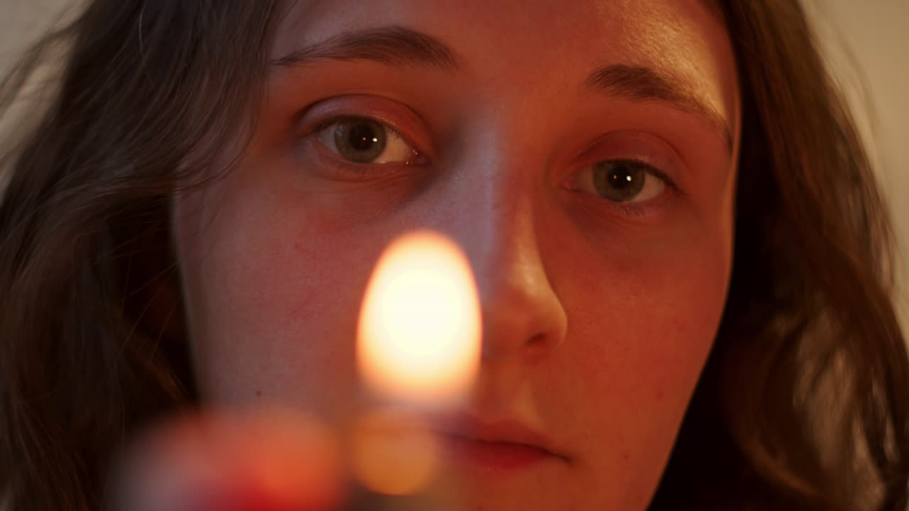 Close up of woman's face looking at camera and lighting lighter. Handheld