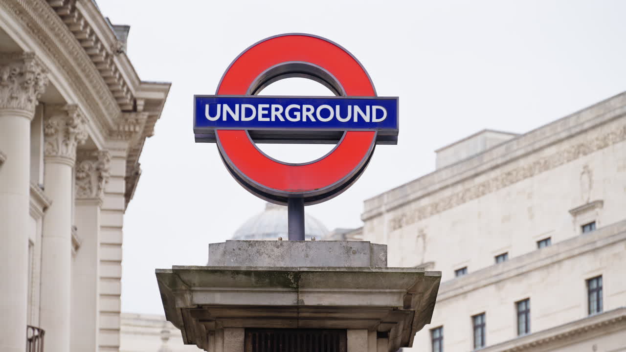 London Underground entrance sign in daylight, framed by neoclassical architecture and urban background