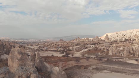 Rugged-barren-landscape-dotted-with-fairy-chimneys,-conned-rock-like-structures-in-Cappadocia,-Turkey---Low-angle-fly-by-Aerial-shot