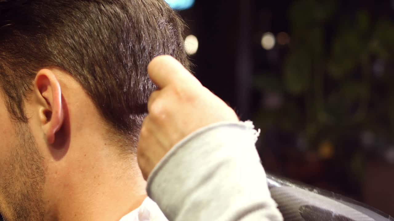 한 남자가 이발소에서 헤어 드라이어로 머리카락을 건조시키고 있다.