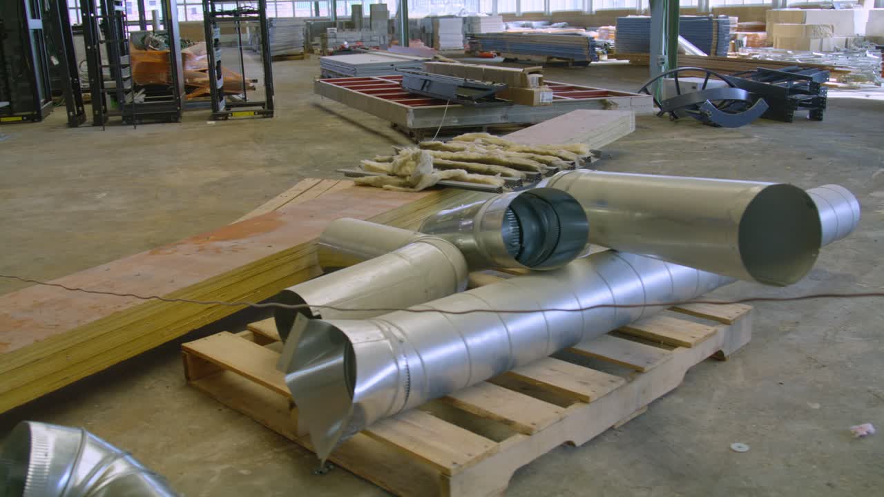 Construction site dolly right to left of some pipes and a pallet