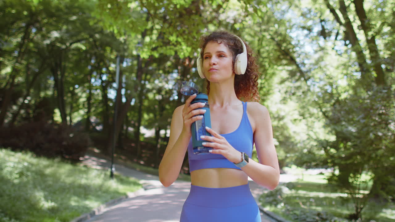 atleta, atleta, corredora, chica bebiendo agua de la botella después de un entrenamiento de cardio en el parque